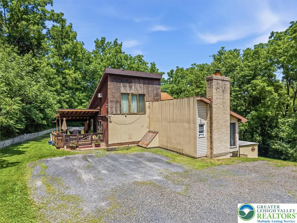 5340 2nd Street Whitehall, PA 18052 - Photo 3 of 30 A charming rustic retreat nestled amongst abundant trees, featuring a spacious deck and a sturdy brick chimney.