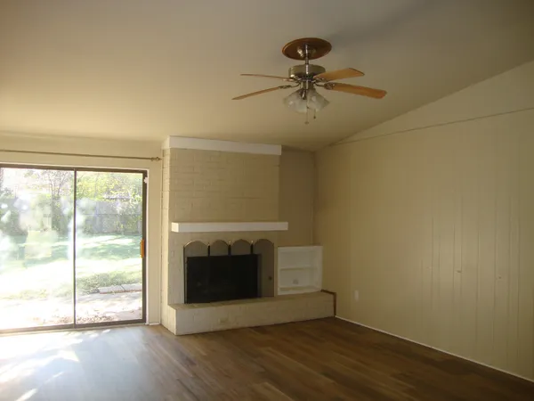 an empty room with wooden floor fireplace and windows