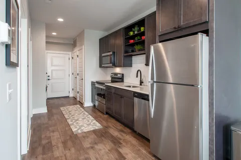 a kitchen with stainless steel appliances granite countertop a refrigerator a stove a sink and a microwave