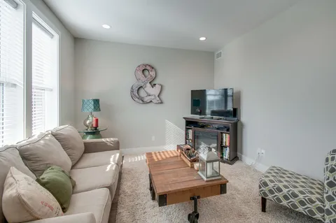 a living room with furniture a flat screen tv and a window