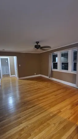 a view of an empty room with wooden floor and a window
