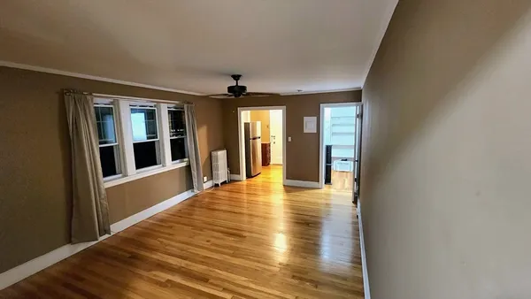 a view of an empty room with wooden floor and a window