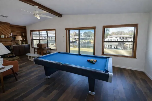 a room with furniture pool table wooden floor and windows