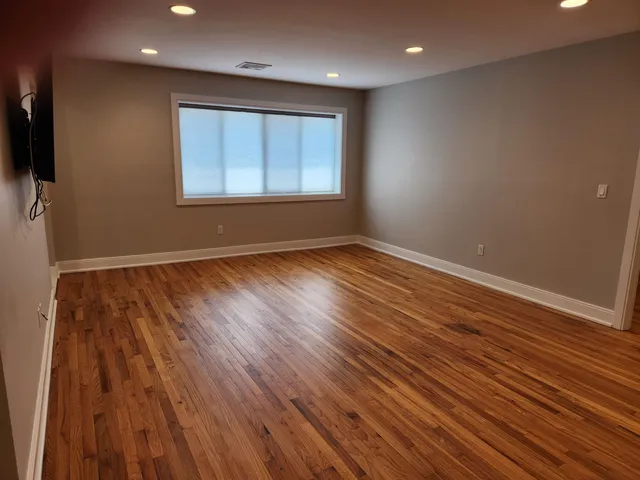 a view of an empty room with wooden floor and a sink