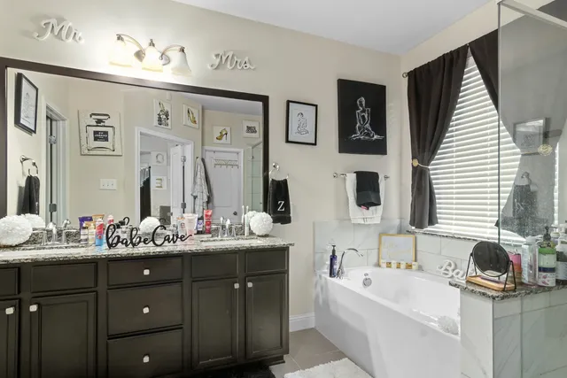 a bathroom with a double vanity sink a mirror and a bathtub