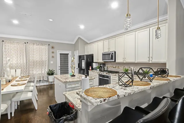 a room with stainless steel appliances kitchen island granite countertop a sink a stove and a refrigerator