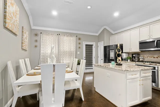 a kitchen that has a dining table chairs and a refrigerator