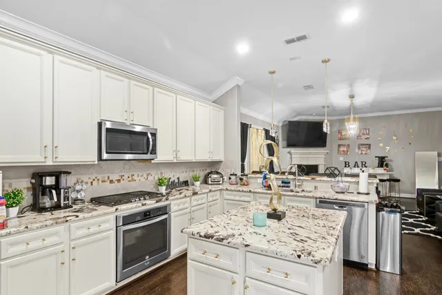 a kitchen with stainless steel appliances kitchen island granite countertop a sink a stove and cabinets