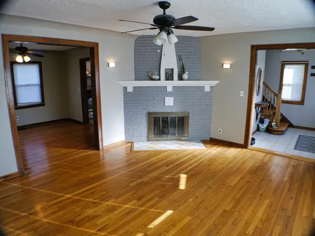 a view of an empty room with wooden floor and a fireplace