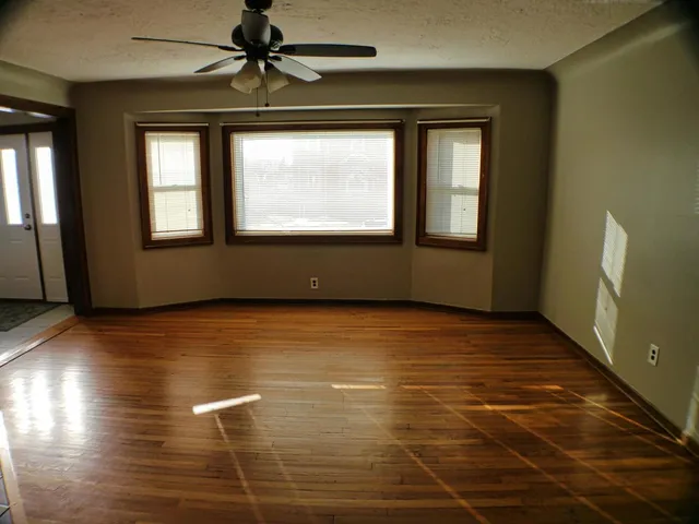 a view of an empty room with window and wooden floor