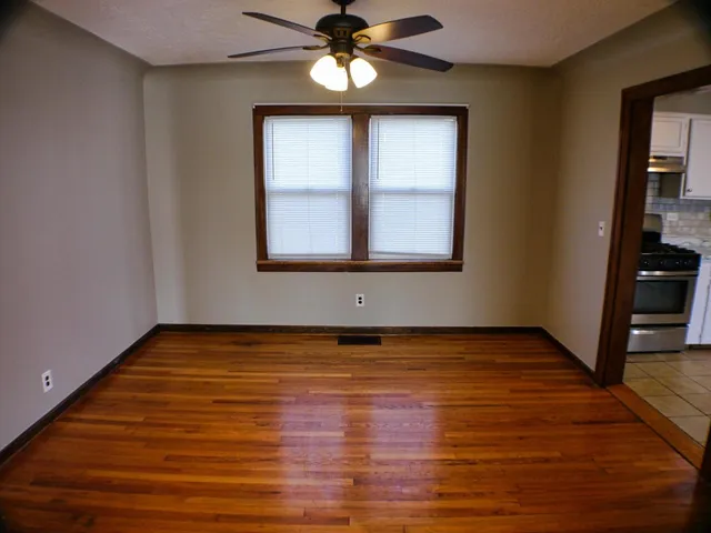 a view of an empty room with wooden floor and a window