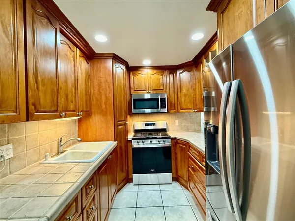 a kitchen with stainless steel appliances granite countertop a refrigerator a sink and wooden cabinets