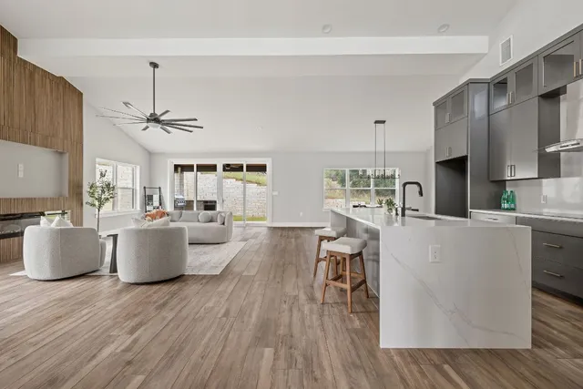 a living room with couches and kitchen view with wooden floor