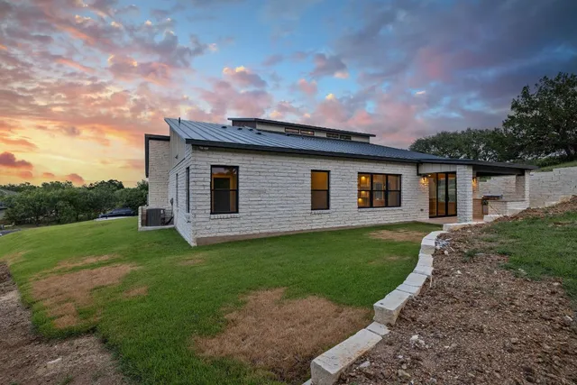a backyard of a house with plants and large trees