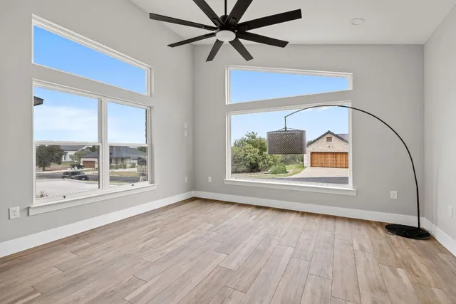 a view of a big room with wooden floor and windows