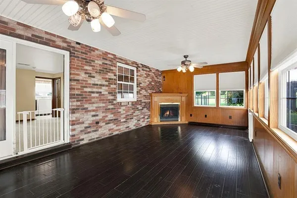 an empty room with wooden floor fan and windows