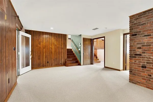 a view of an empty room with wooden floor and stairs