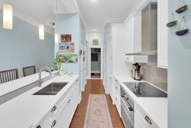 a large white kitchen with a sink and a large window