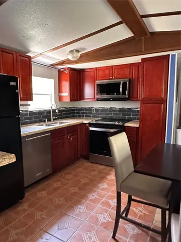 a kitchen with stainless steel appliances granite countertop a sink and a refrigerator