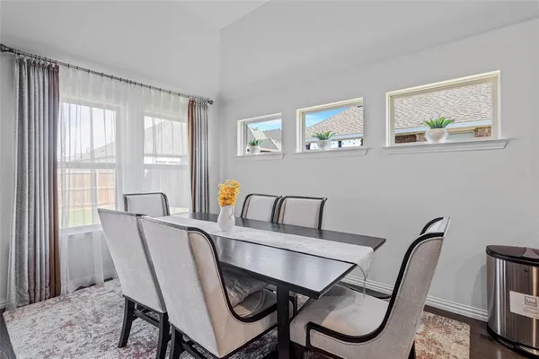 a view of a dining room with furniture a rug and wooden floor