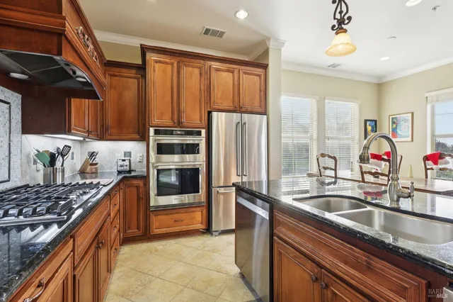 a kitchen with kitchen island granite countertop a sink stainless steel appliances and cabinets