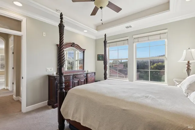 a bedroom with a bed next to a window with a chandelier