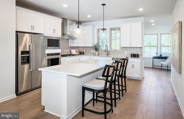 a kitchen with stainless steel appliances a dining table chairs stove refrigerator and cabinets