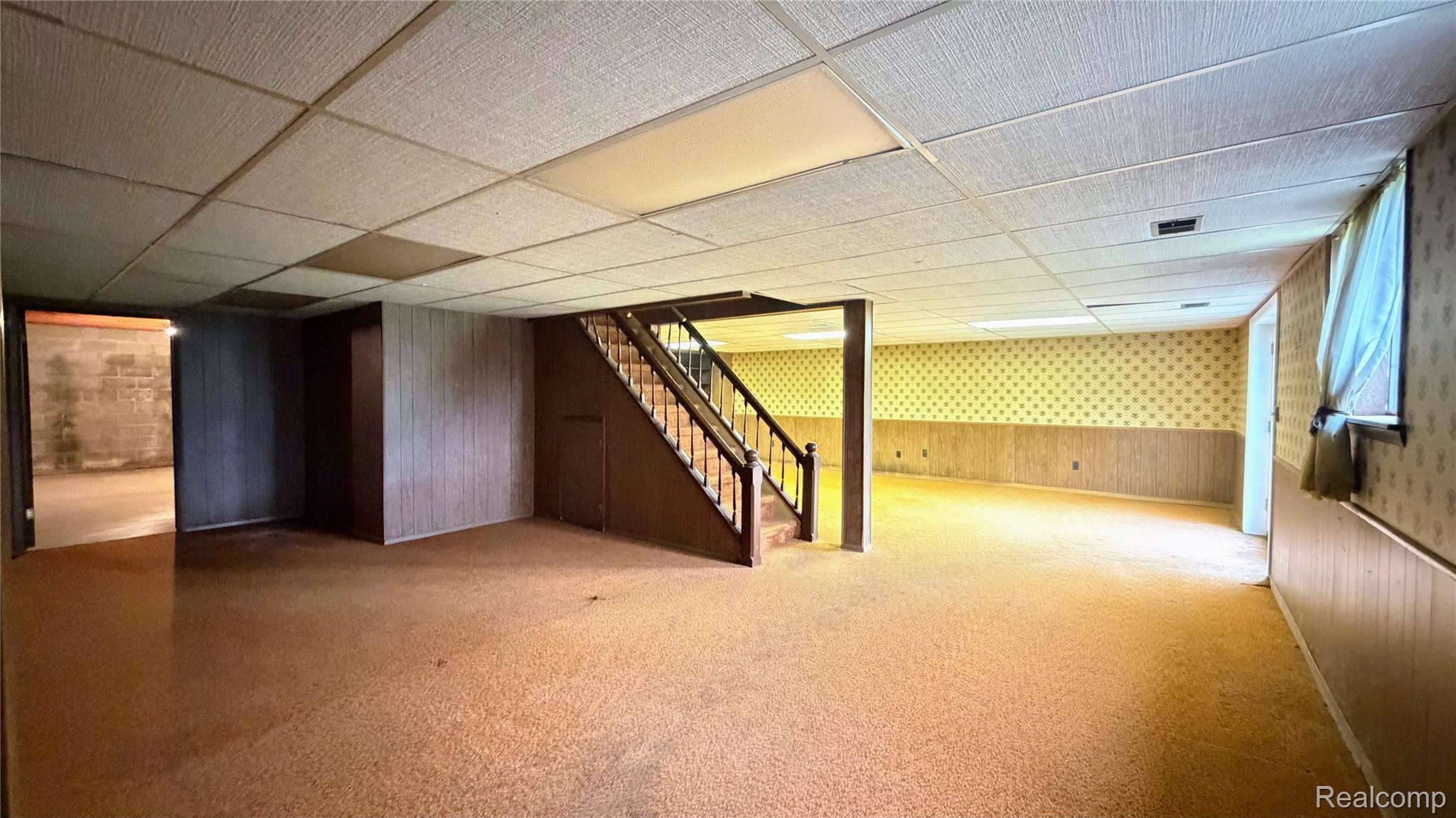 8079 Farley Road Pinckney, MI 48169 - Photo 28 of 43 Finished basement with wooden walls, a wainscoted wall, a drop ceiling, carpet floors, and wallpapered walls