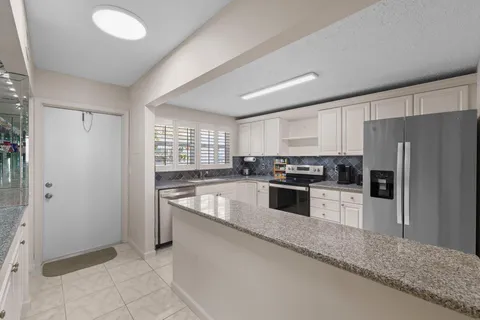 a kitchen with granite countertop a refrigerator and a stove top oven