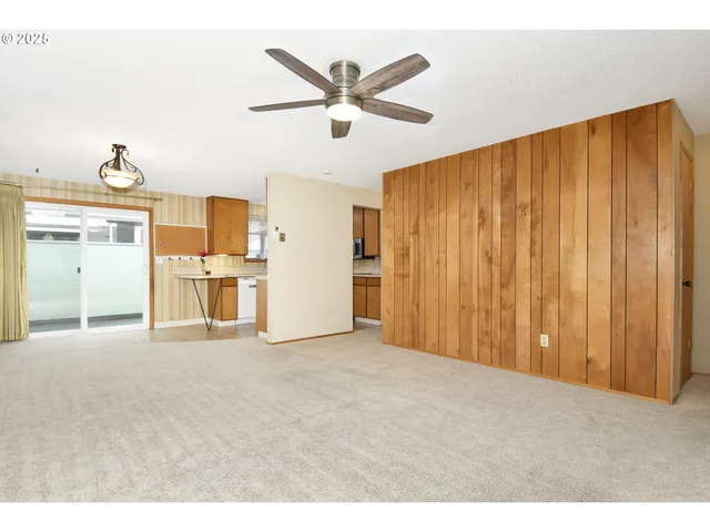 a view of a livingroom with a ceiling fan & kitchen view