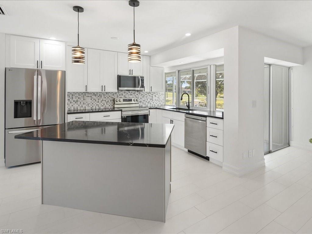 262 Torrey Pines Point Naples, FL 34113 - Photo 4 of 24 a kitchen with stainless steel appliances kitchen island granite countertop a stove a sink and a refrigerator
