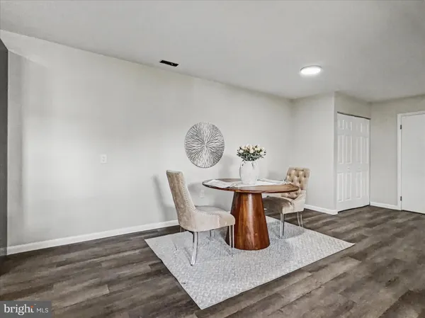 a dining room with wooden floor and white walls