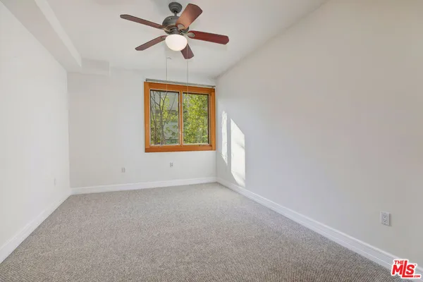 an empty room with windows and fan