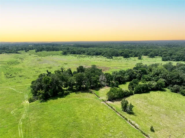a view of a green field with trees in the background