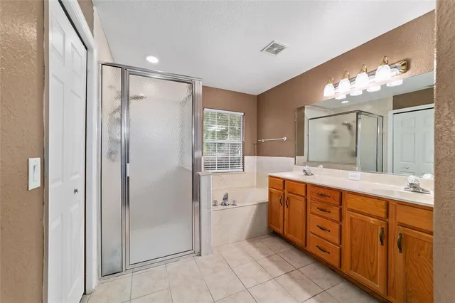 a spacious bathroom with a double vanity sink a large mirror and a bathtub