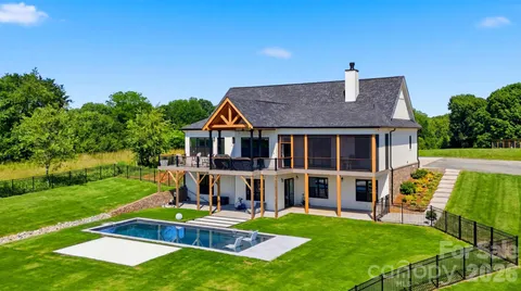 a aerial view of a house next to a big yard with plants and large trees