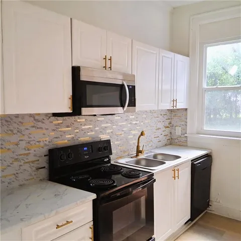 a kitchen with granite countertop white cabinets stainless steel appliances and window