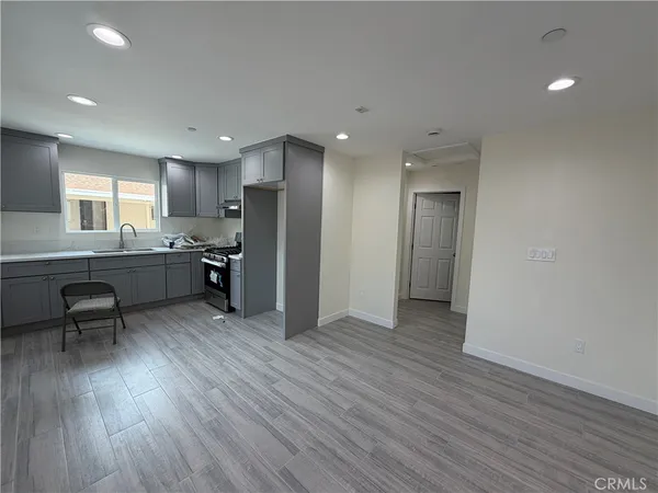 a kitchen with stainless steel appliances granite countertop a refrigerator a sink dishwasher a stove and a dining table with wooden floor