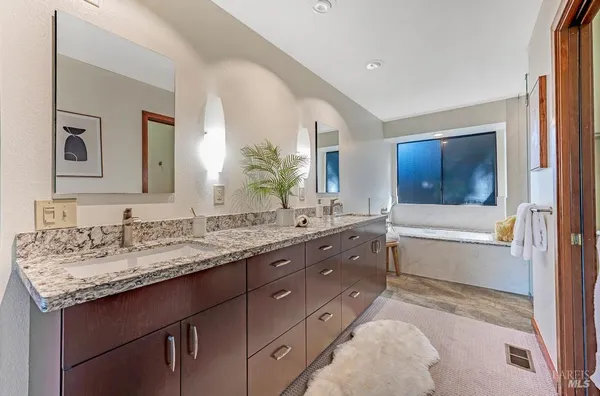 a bathroom with a granite countertop double vanity sink a mirror and a