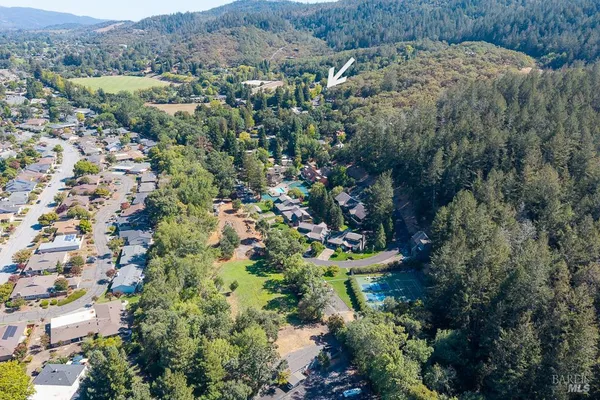 an aerial view of residential house with outdoor space and trees all around