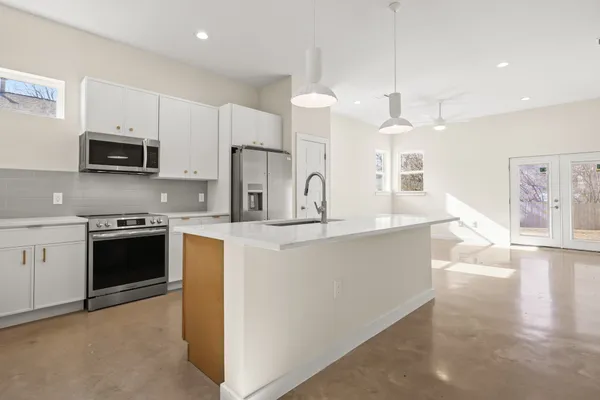 a large kitchen with stainless steel appliances a sink a stove a refrigerator a center island a stove and cabinets