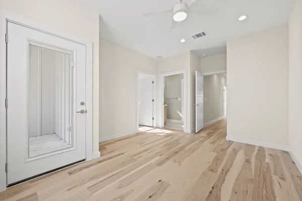 a view of an empty room with wooden floor and door