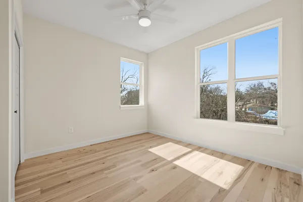 an empty room with wooden floor and windows