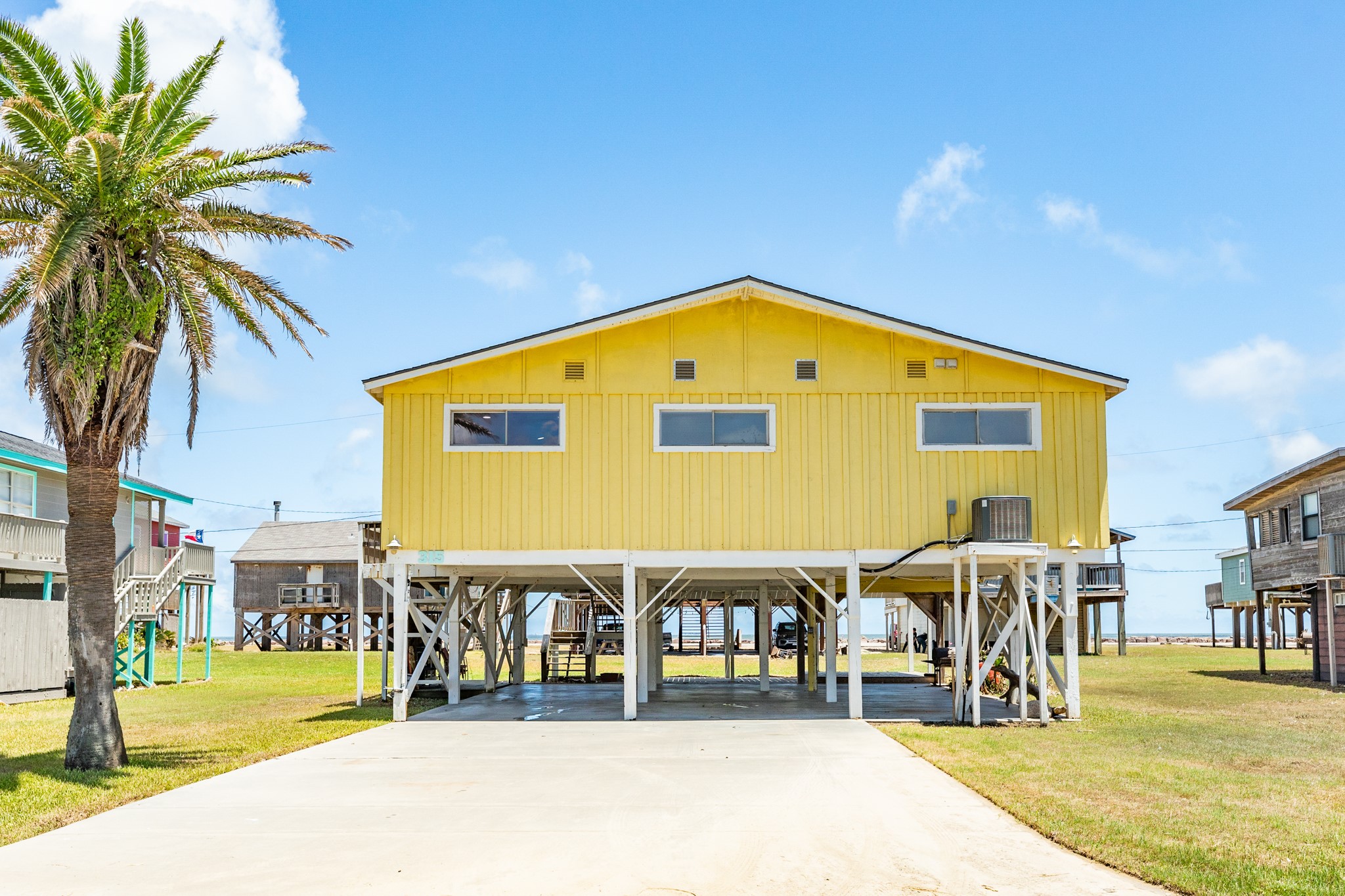315 Seashell Drive Surfside Beach, TX 77541 - Photo 27 of 33 Driveway View – Wide concrete driveway with room for multiple vehicles, leading to the home’s elevated main entry.