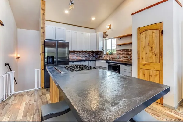 a view of a kitchen with kitchen island a sink wooden floor and a refrigerator