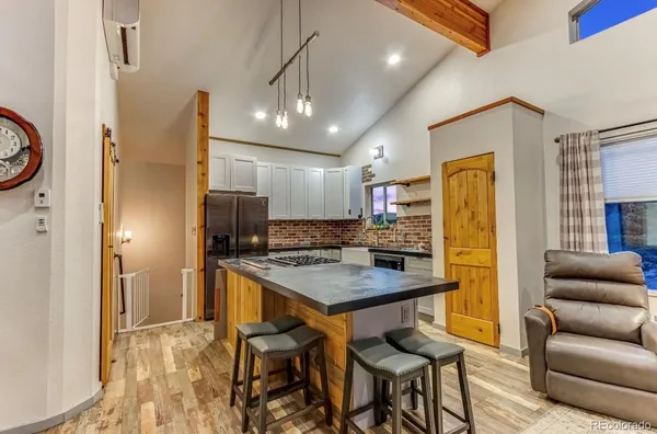 a kitchen with stainless steel appliances kitchen island granite countertop a refrigerator a stove a oven a dining table and chairs with wooden floor