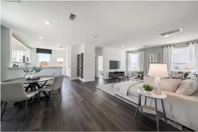 a living room with furniture a wooden floor and a kitchen view