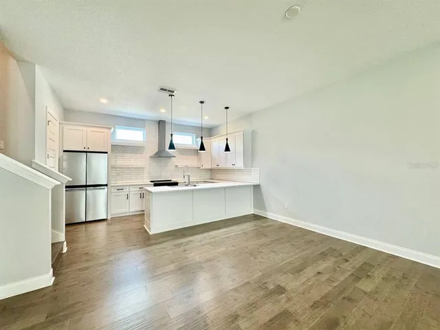 a large kitchen with a refrigerator a stove a microwave and white cabinets