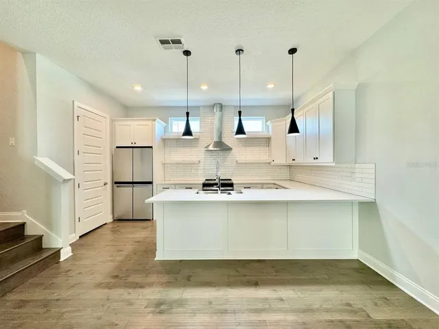 a view of kitchen with kitchen island white cabinets and stainless steel appliances