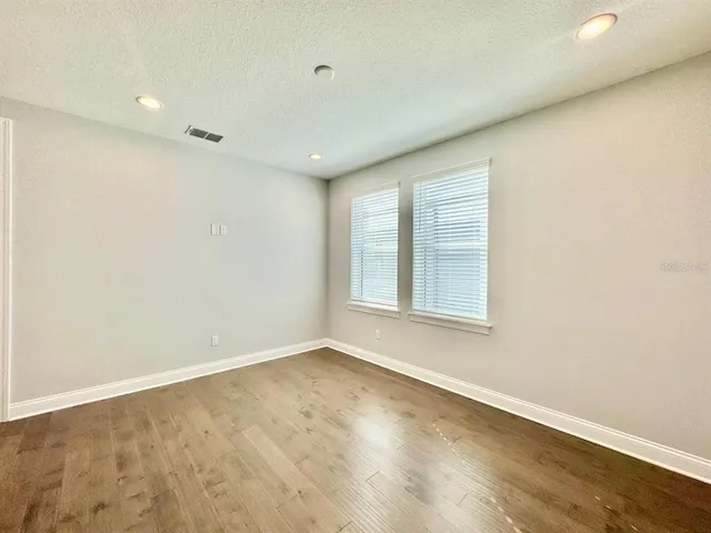 an empty room with wooden floor and windows